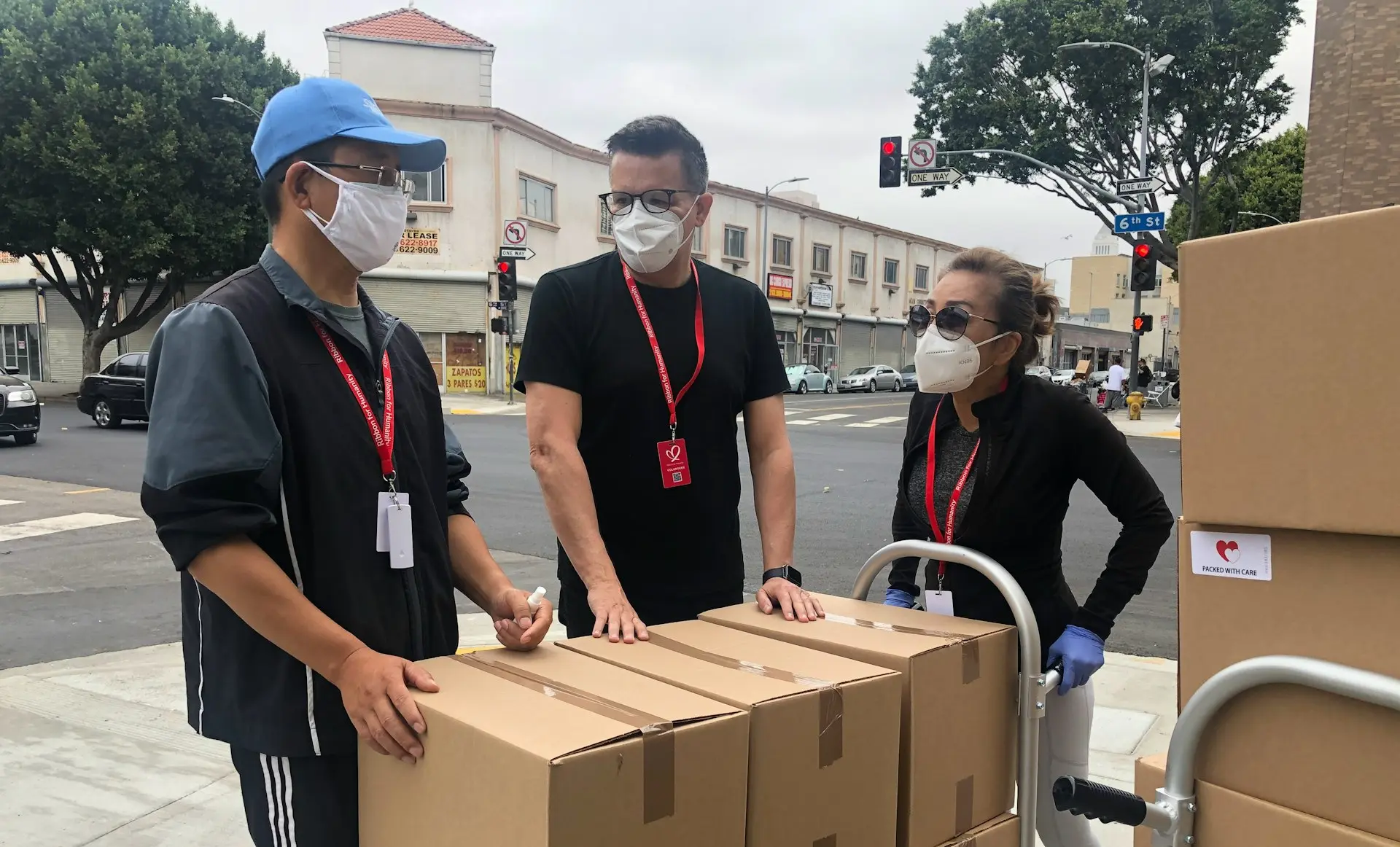 3 men in black polo shirt standing beside brown cardboard boxes