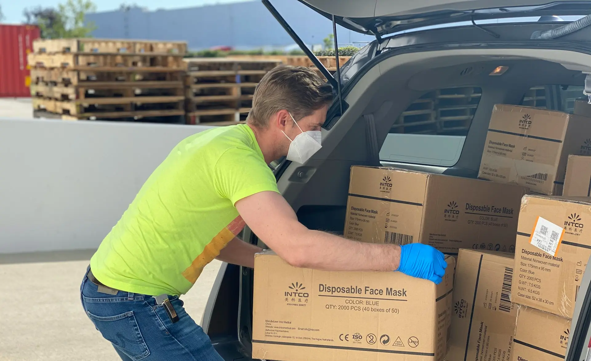 man in green t-shirt and blue denim jeans holding brown cardboard box